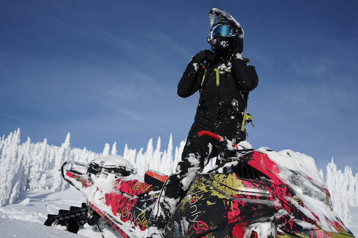 Snowmobile rider on a Bulletproof Graphics wrapped sled in deep mountain snow