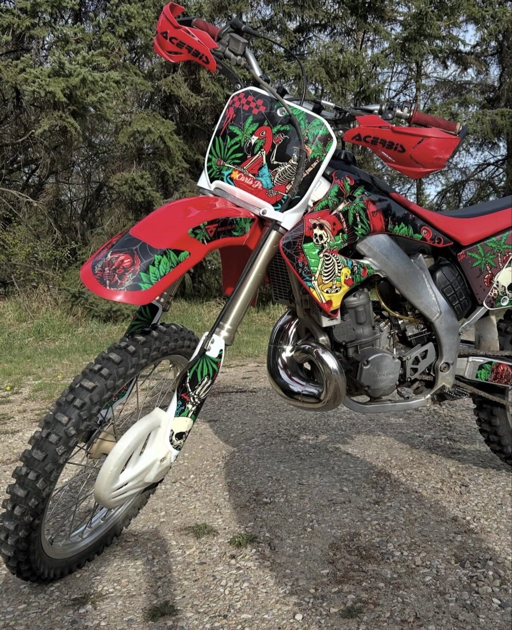 Red dirt bike with custom tropical skeleton graphics by Bulletproof Graphics