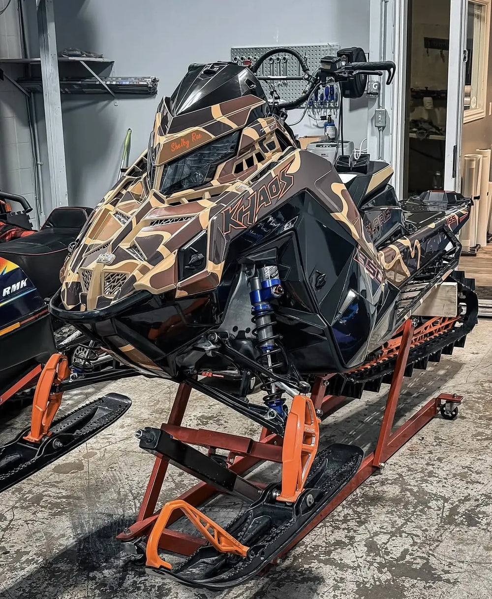 Tan and black camouflage graphics on a snowmobile in the workshop